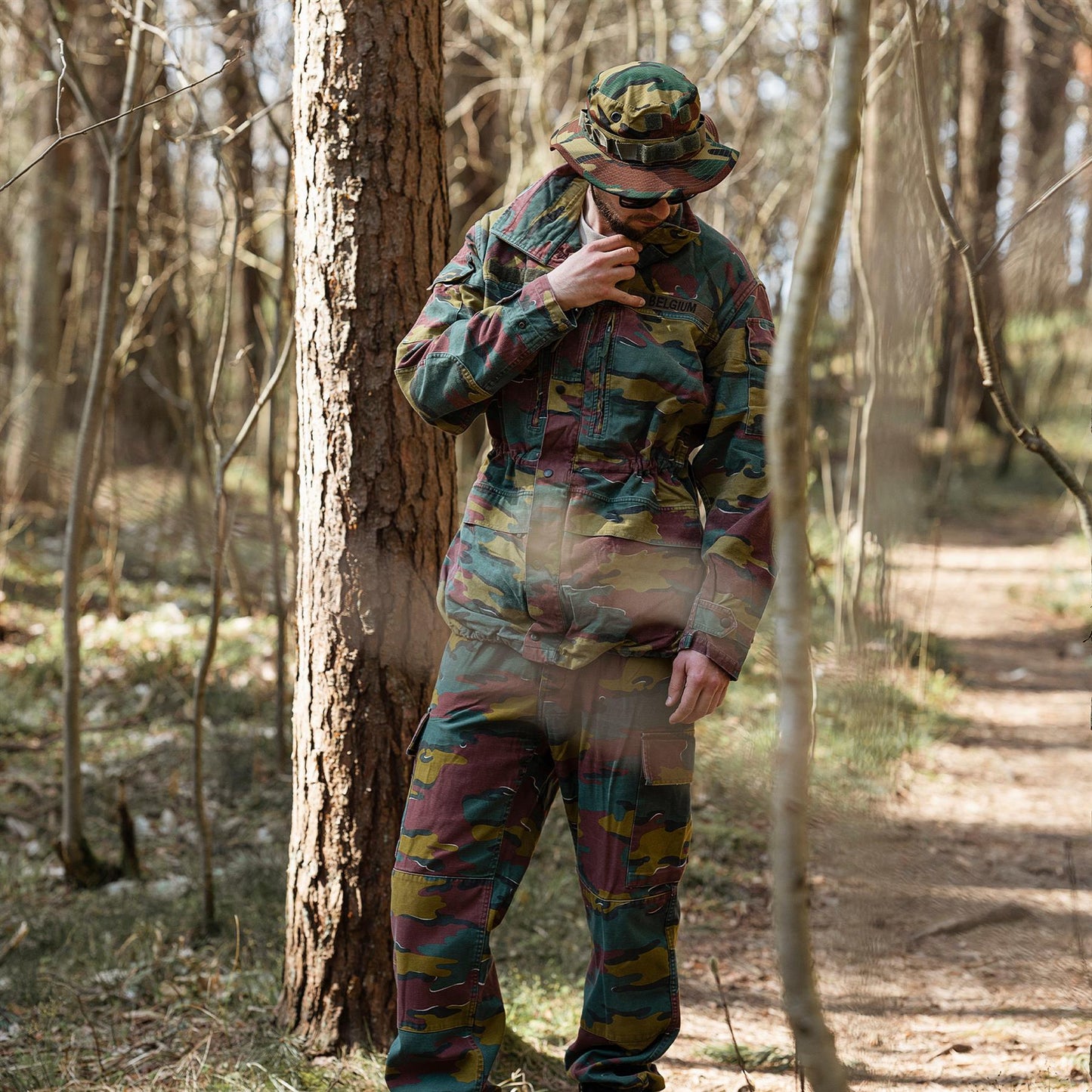 Žmogus dėvi Belgijos kariuomenės lauko kelnes M90 Jigsaw miško kamufliažo raštu gamtoje.