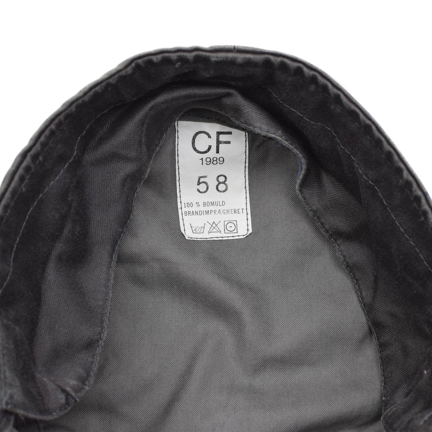 Pilka Danijos kariuomenes kepure su CF 1989 etikete, rodancia 58 dydi, medvilnine struktura ir prieziuros simboliais