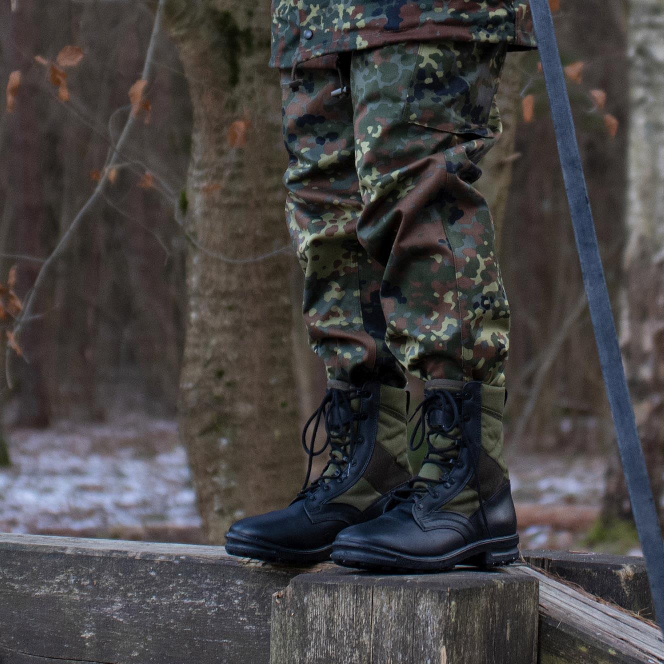 Vokiečių kariuomenės lauko uniformos kelnės Flecktarn marginimo su tvirtais botais lauko aplinkoje.