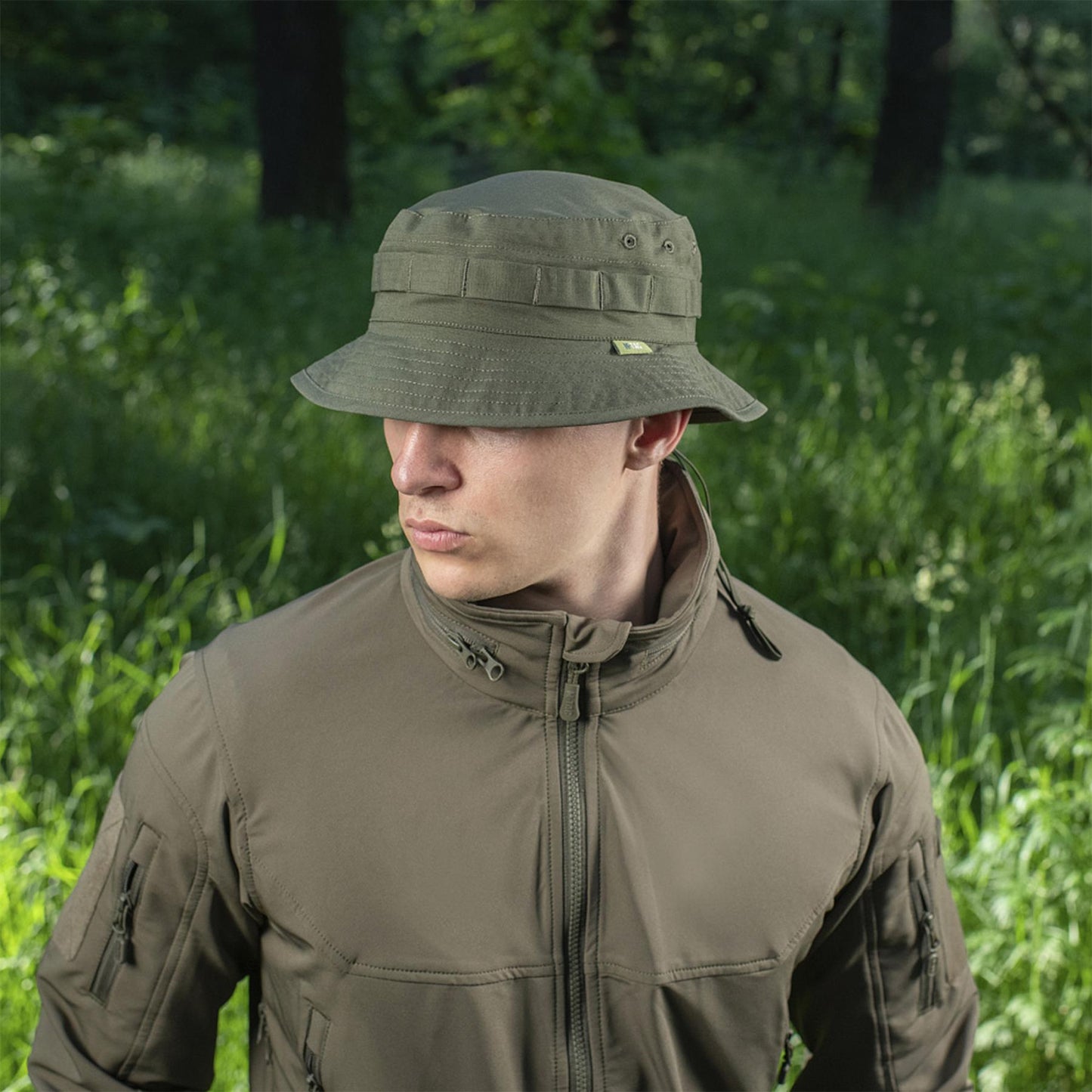 Vyras dėvi M-TAC bucket stiliaus kepurę alyvuogių spalvos lauko entuziastams ir medžioklei.