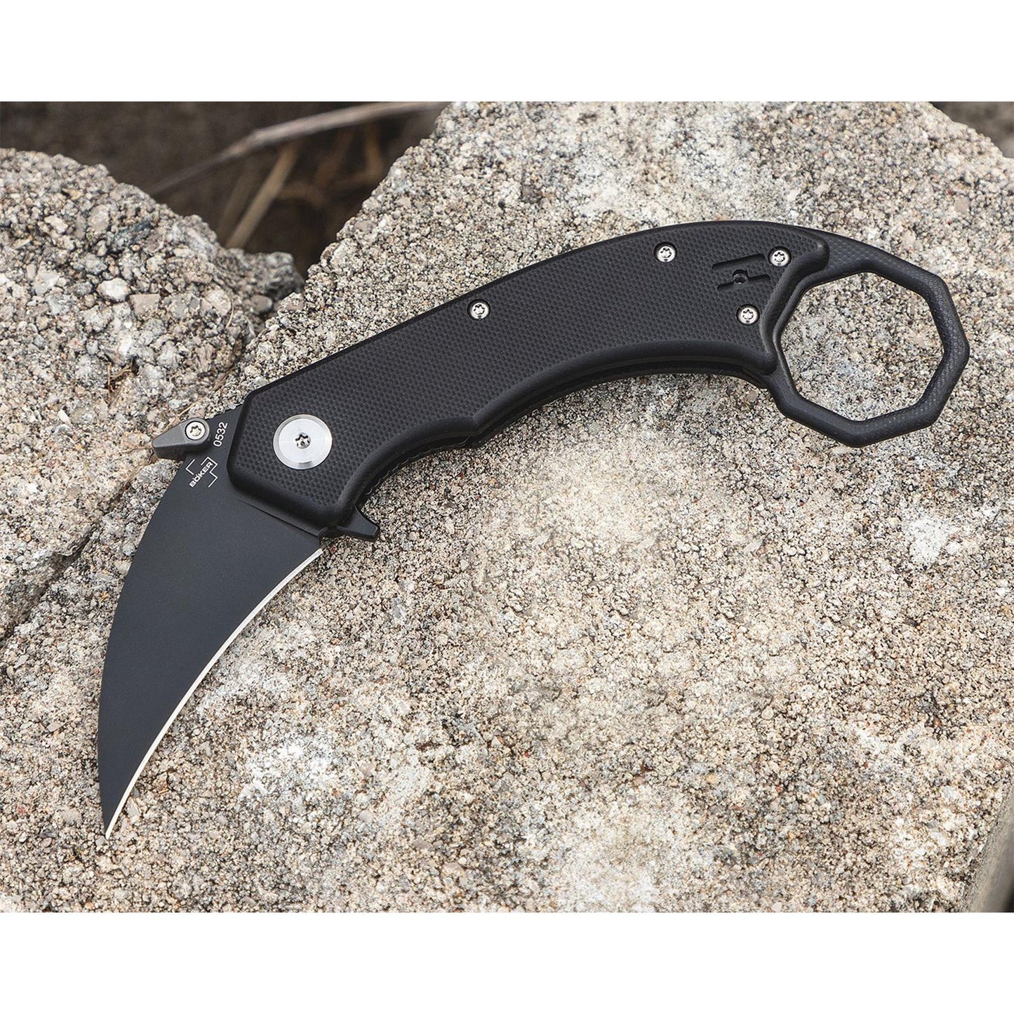 Boker Plus HEL taktinis sulankstomas karambitas su juoda hawkbill geležte ir teksturuota rankena ant akmens fono