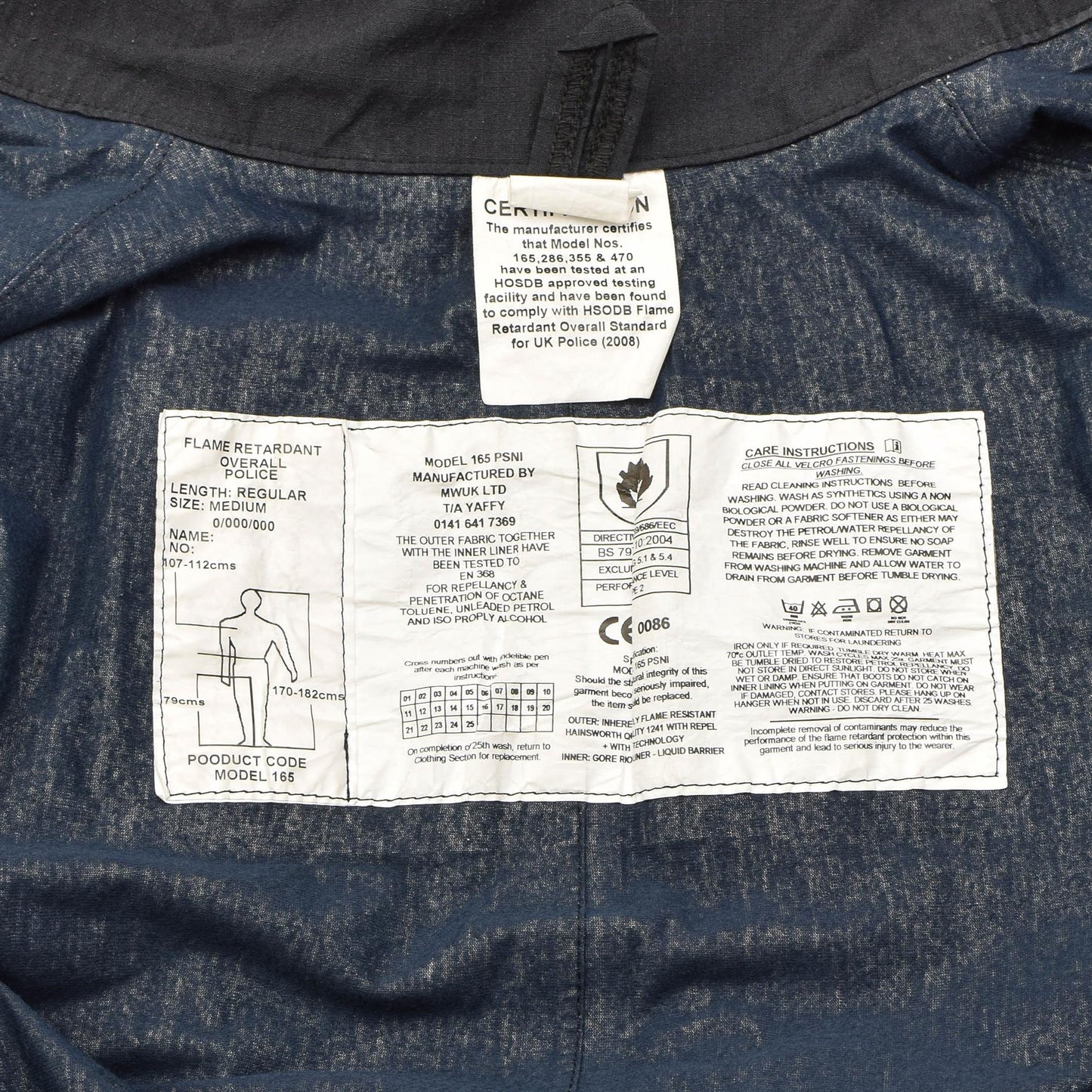 Jungtinės Karalystės policijos kombinezonas vandenui ir ugniai atsparus juodos spalvos etiketė su dydžio ir priežiūros instrukcijomis.