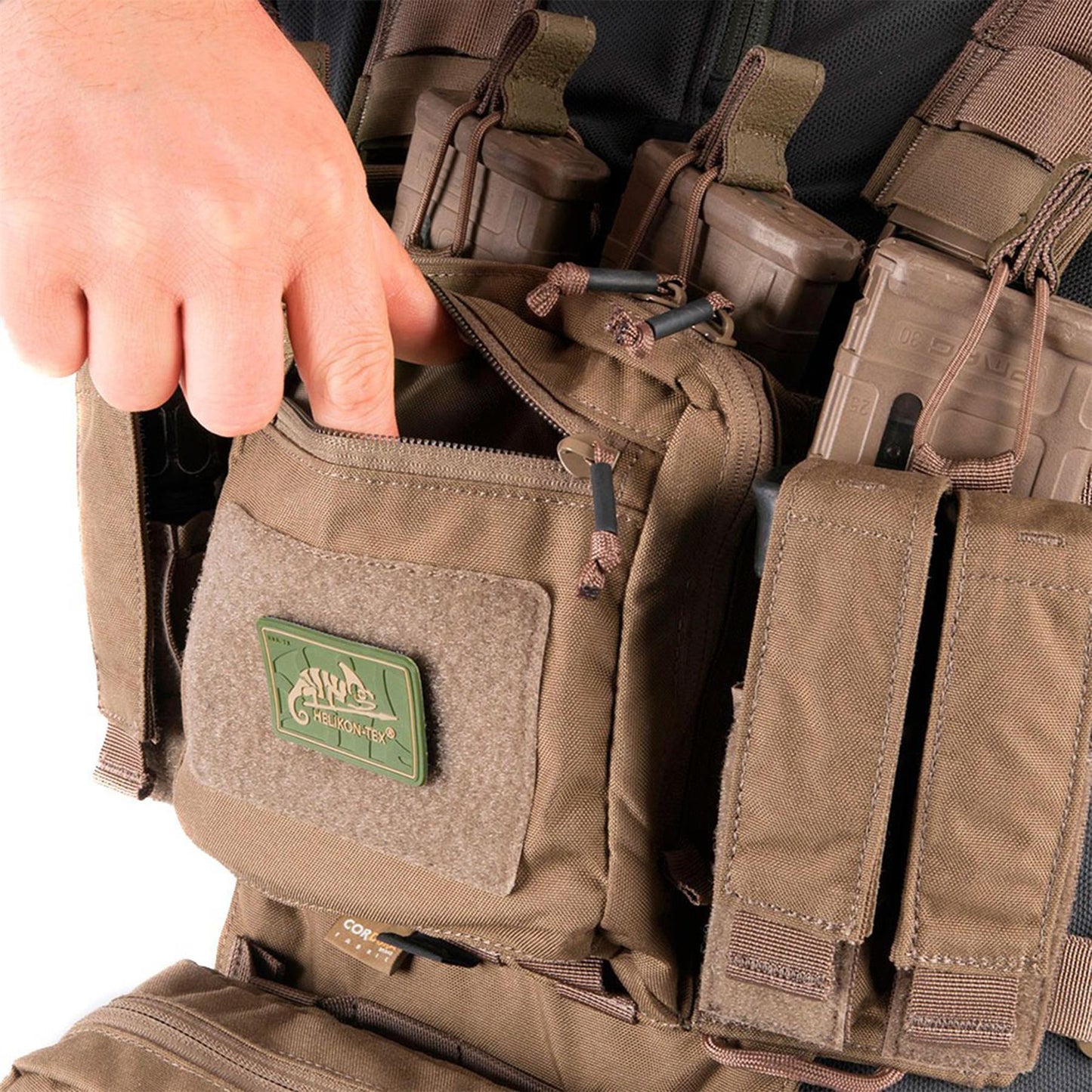 Helikon-Tex Chest Rig treniruočių taktinė liemenė Multicam, rodoma ranka atidaro priekinę kišenę.