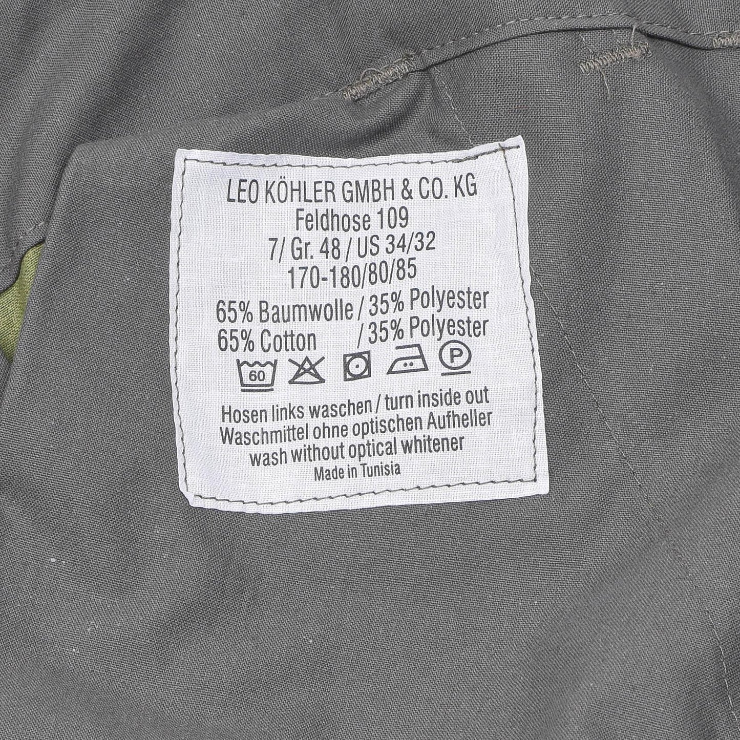 Leo Kohler taktinės lauko uniformos kelnės Flecktarn marginimas audinio etiketė su sudėtimi ir priežiūros instrukcija.